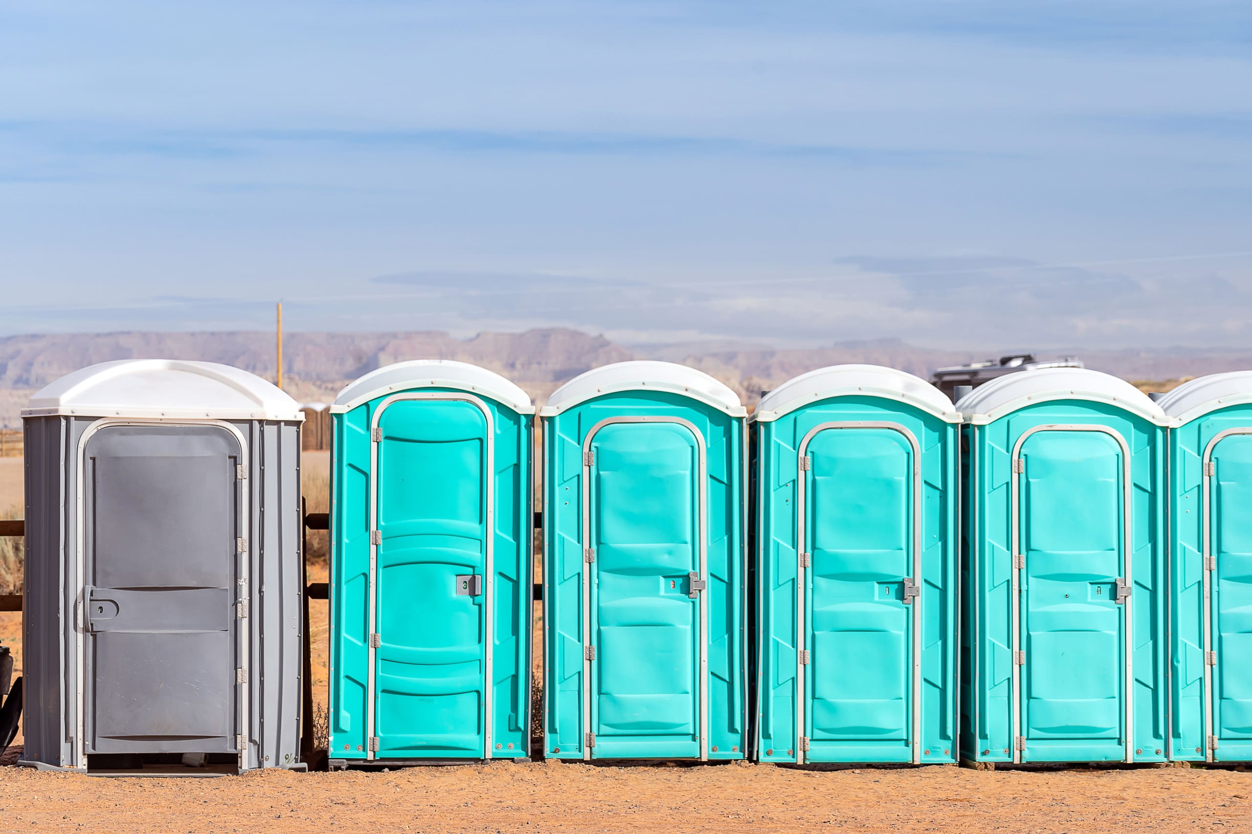 A row of grey and blue portable toilets