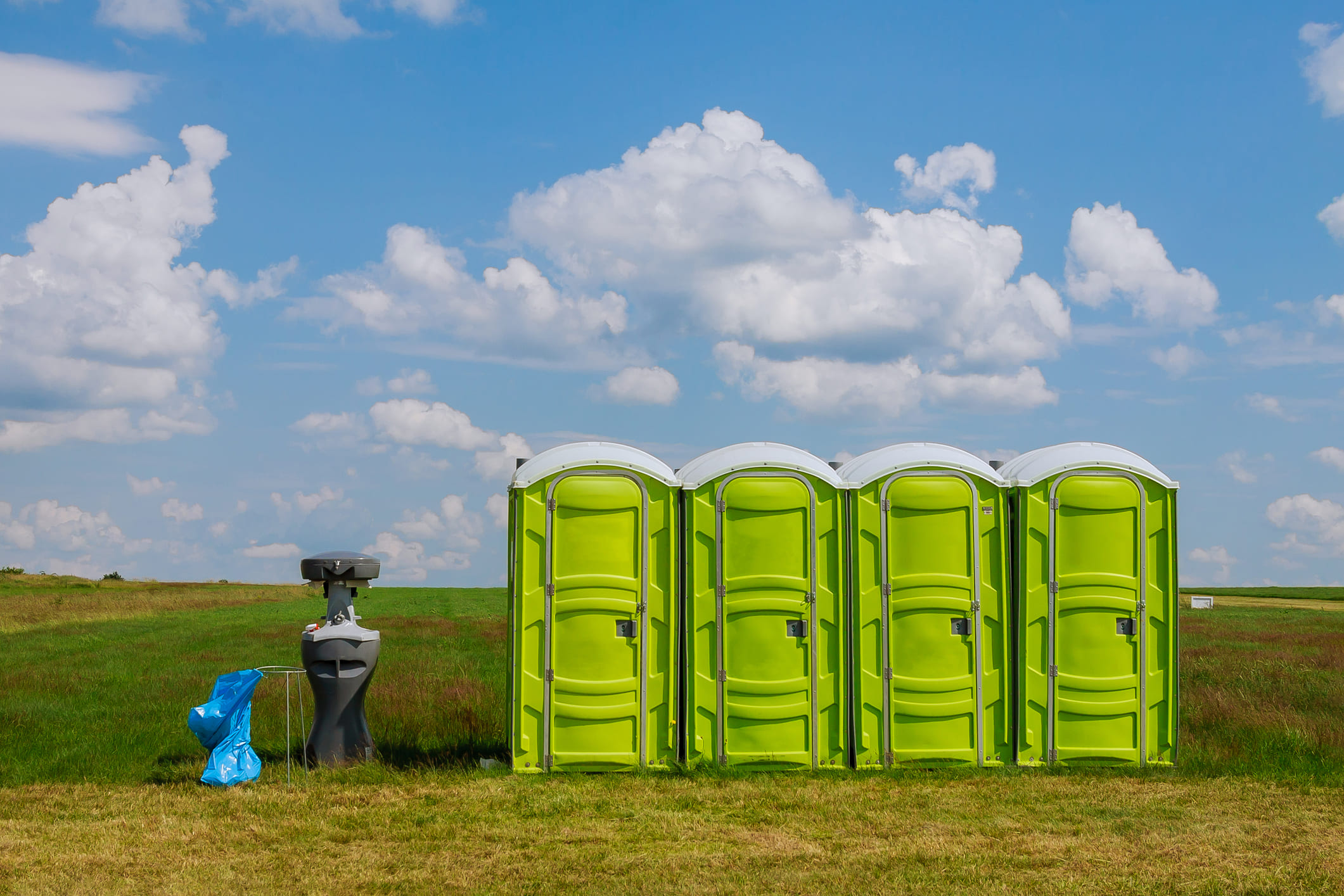 Portable toilet on the grass on a background of clouds